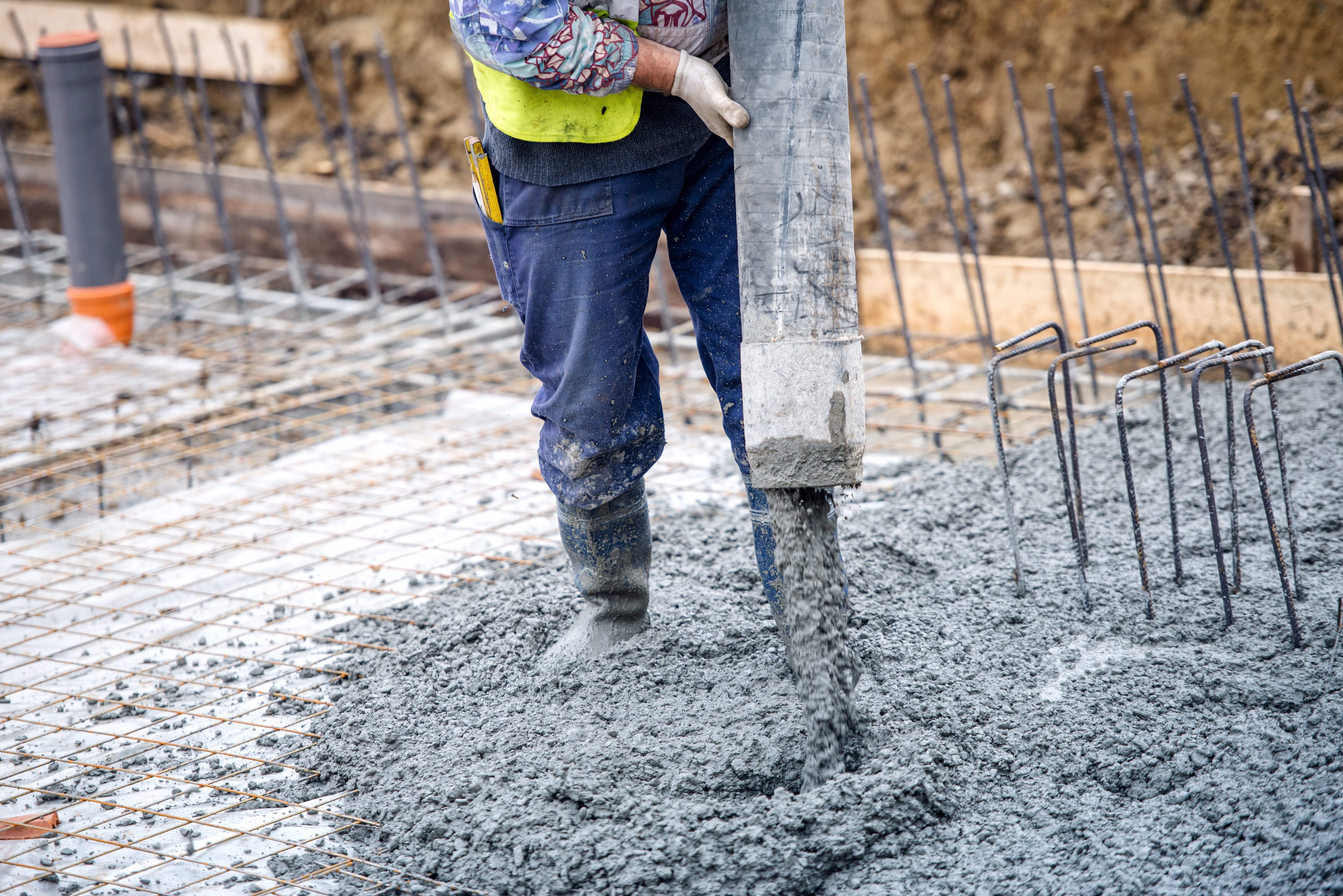construction worker pouring cement or concrete with pump tube - Grupo BDL